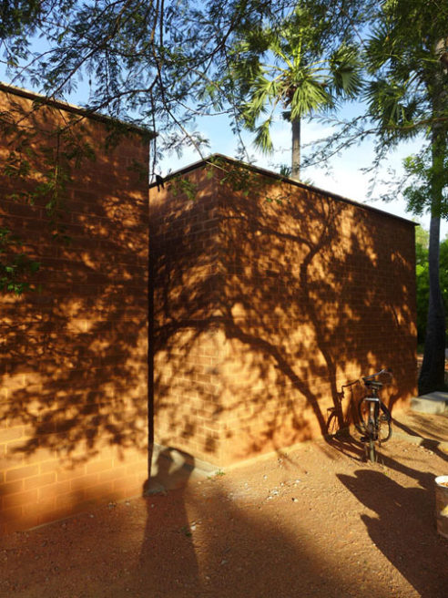 shadow of trees covering earth brick building at sharanam pondicherry